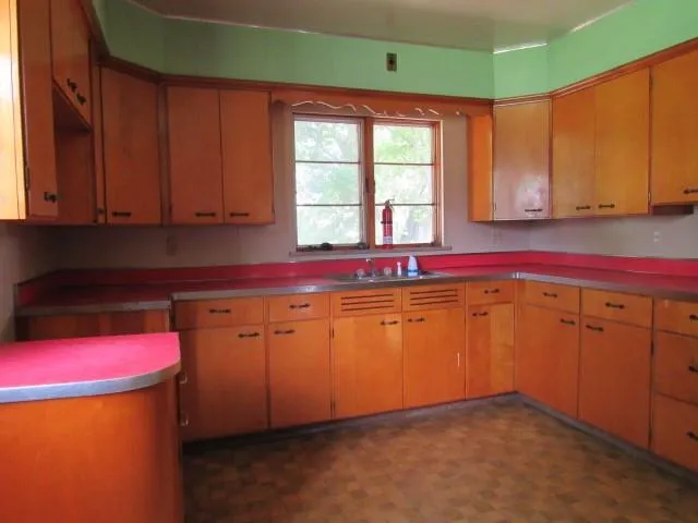 a kitchen with granite countertop a sink a stove cabinets and a window