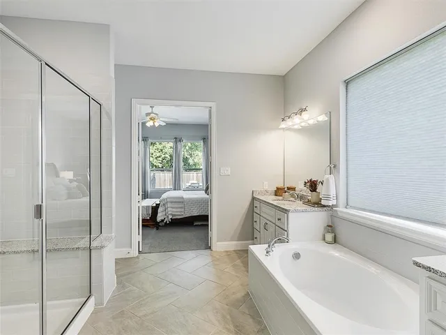 a bathroom with a tub a sink double vanity and a mirror