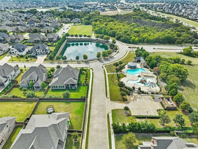 an aerial view of a house with swimming pool and large trees
