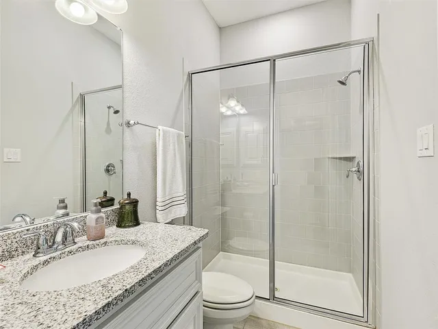 a bathroom with a granite countertop sink toilet and shower