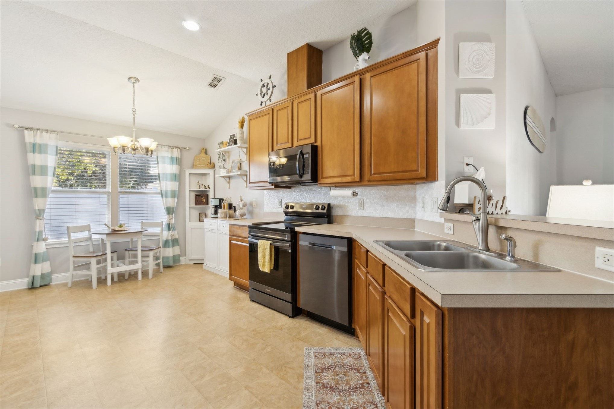 86027 Maple Leaf Place Yulee, FL 32097 - Photo 15 of 38 a kitchen with kitchen island granite countertop a sink stove and cabinets