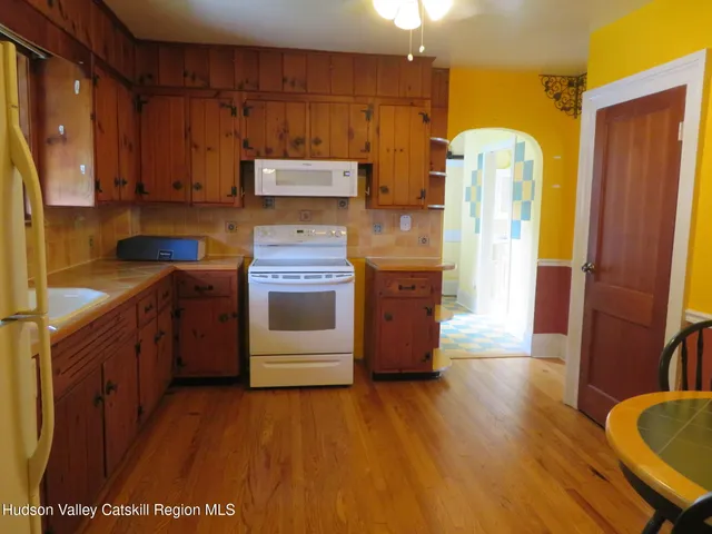 a kitchen with a refrigerator a stove top oven a sink and wooden floor