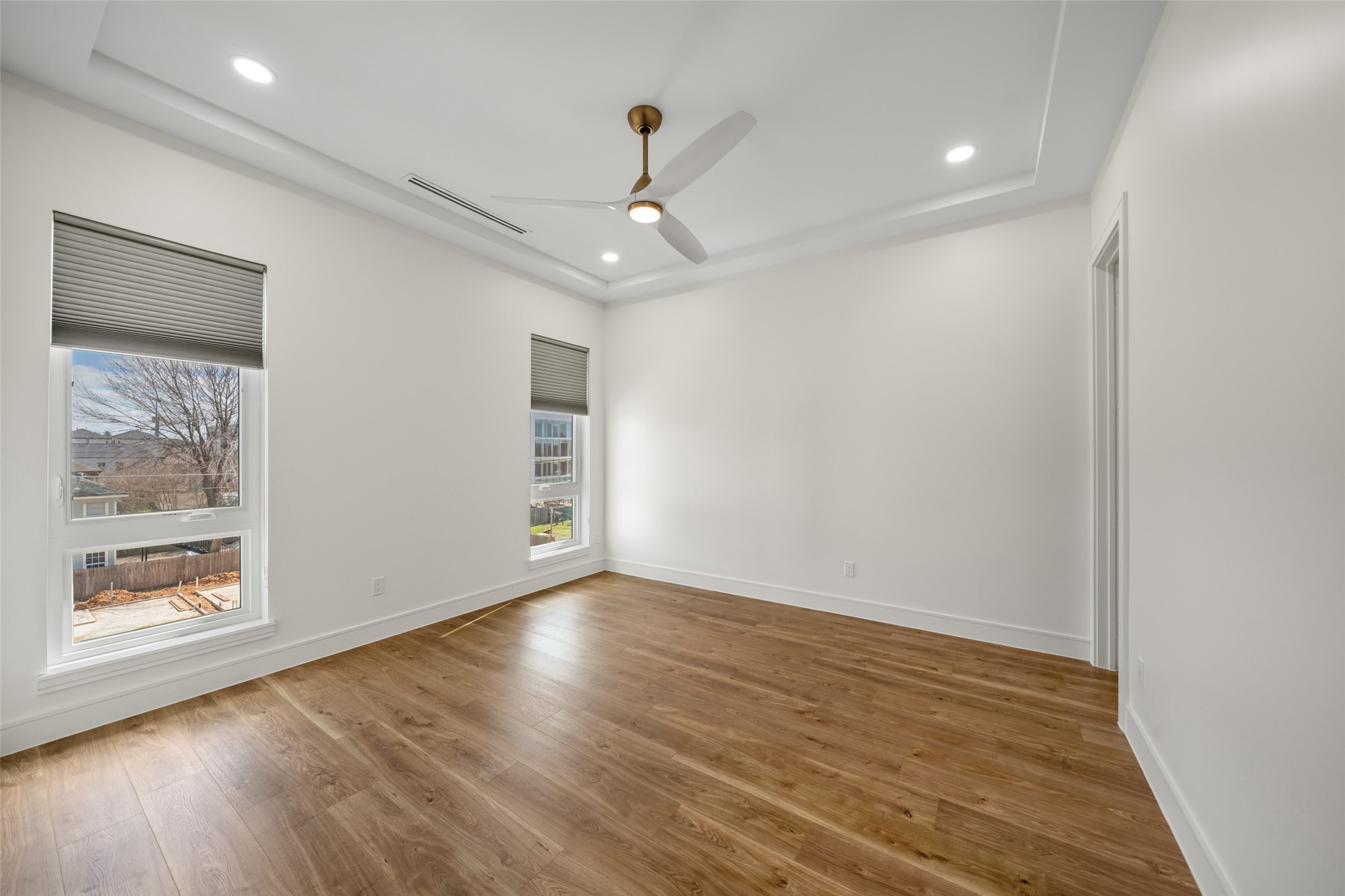 1839 Colquitt Street Houston, TX 77098 - Photo 6 of 19 Bedroom #1 features elegant wood flooring, a modern ceiling fan, and recessed lighting. Large windows provide ample natural light, while the neutral walls offer a blank canvas for personalization.