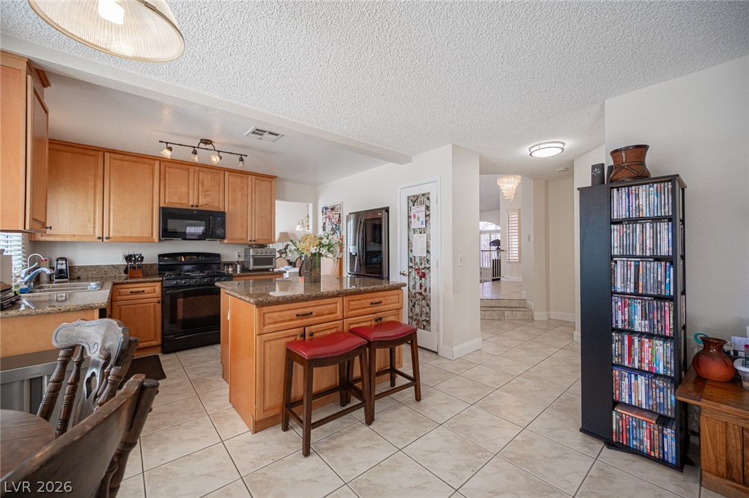 718 Rusty Spur Drive Henderson, NV 89014 - Photo 14 of 50 A well-appointed kitchen features rich wooden cabinetry, stone countertops, and modern appliances, creating a highly functional and inviting space.