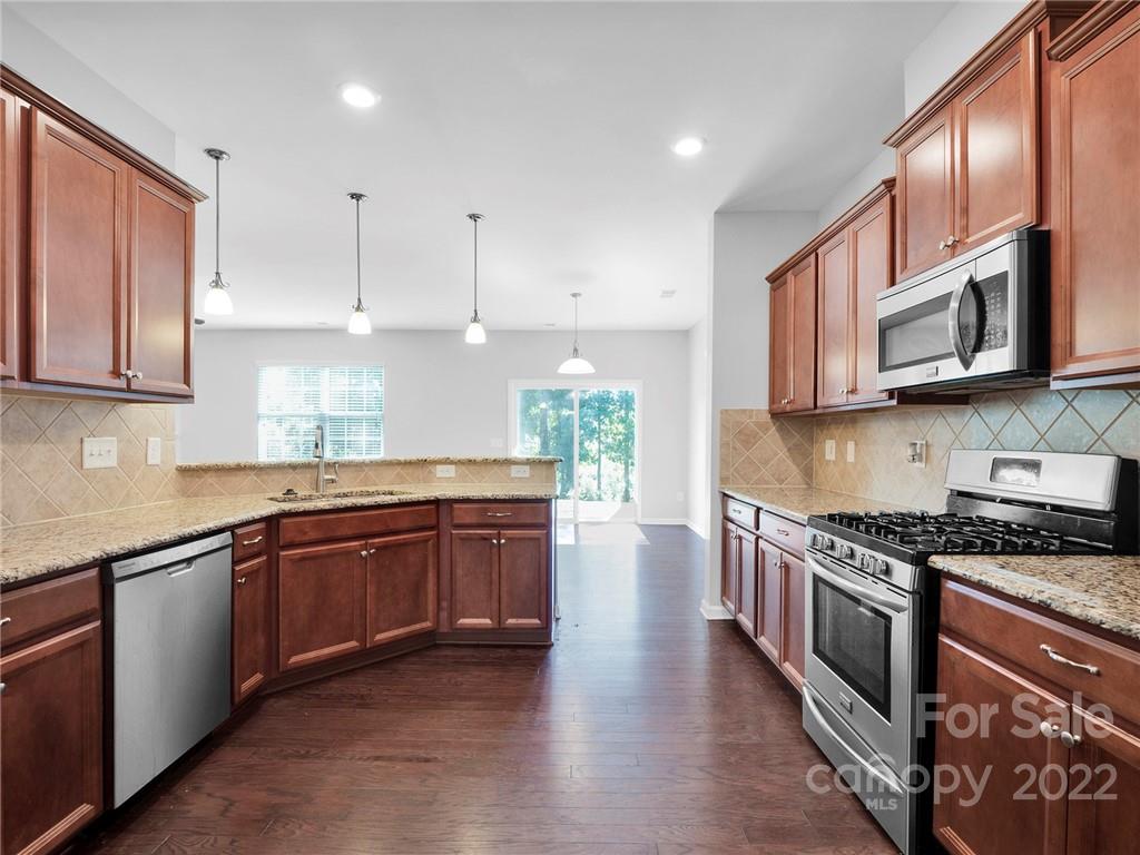 10502 Ebbets Road Charlotte, NC 28273 - Photo 10 of 48 a kitchen with stainless steel appliances granite countertop wooden cabinets a stove a sink and dishwasher with wooden floor