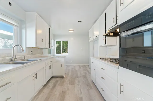 a large kitchen with granite countertop a sink and dishwasher stove a refrigerator with wooden cabinets