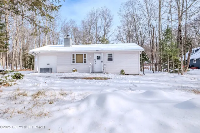 a view of a white house with a yard covered the snow
