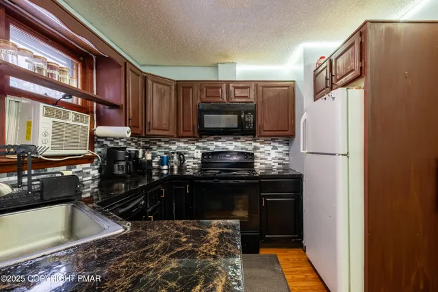 a kitchen with granite countertop a refrigerator stove and sink