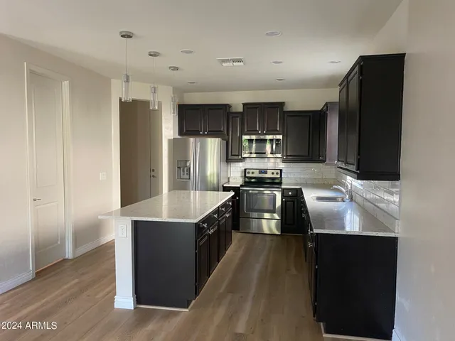 a kitchen with stainless steel appliances a refrigerator a sink a stove and cabinets