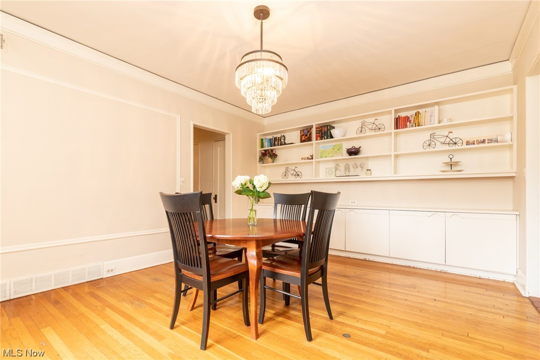 2515 Overlook Road, Unit 14 Cleveland, OH 44106 - Photo 7 of 20 Dining area with an inviting chandelier, crown molding, built in shelves, and light wood-type flooring