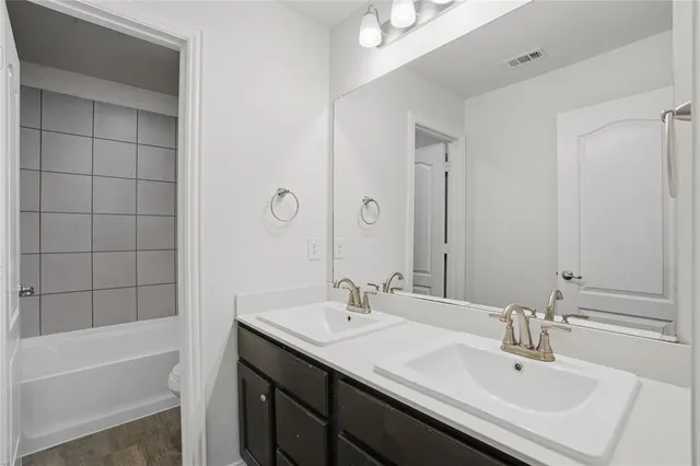 a bathroom with a sink double vanity granite tub shower and a mirror