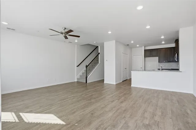 a view of an empty room with wooden floor and a ceiling fan