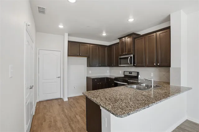 a kitchen with kitchen island granite countertop stainless steel appliances granite countertop a sink refrigerator and microwave