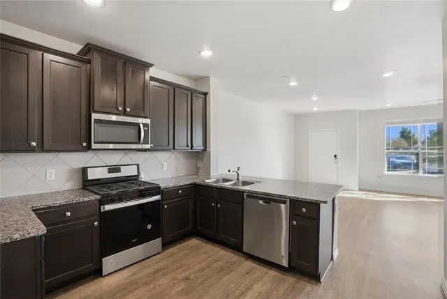 a kitchen with stainless steel appliances granite countertop a sink stove and microwave