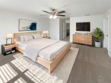 a spacious bedroom with a bed and a flat screen tv