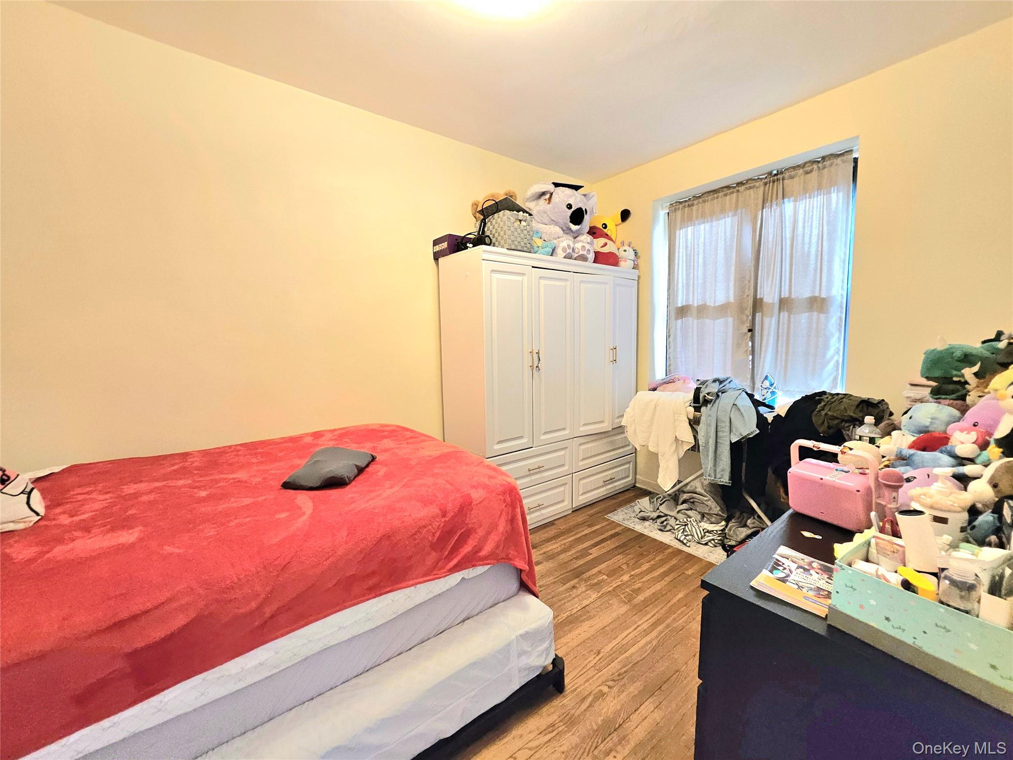 112-25 34th Avenue, Unit H Queens, NY 11368 - Photo 19 of 20 a bedroom with a bed and wooden floor