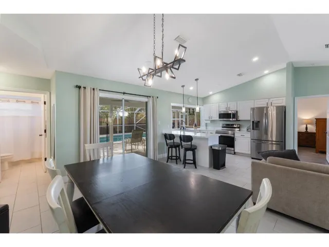 a view of a dining room and livingroom with furniture wooden floor a chandelier