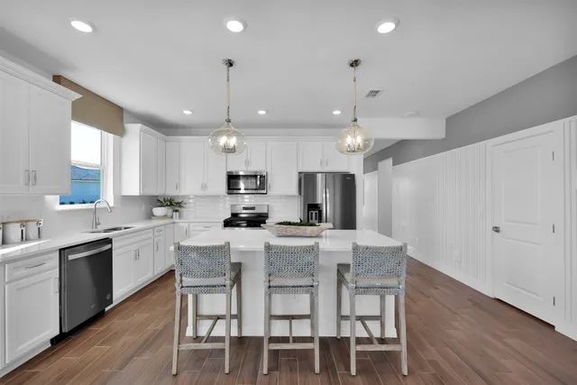 a large kitchen with cabinets chairs and wooden floor