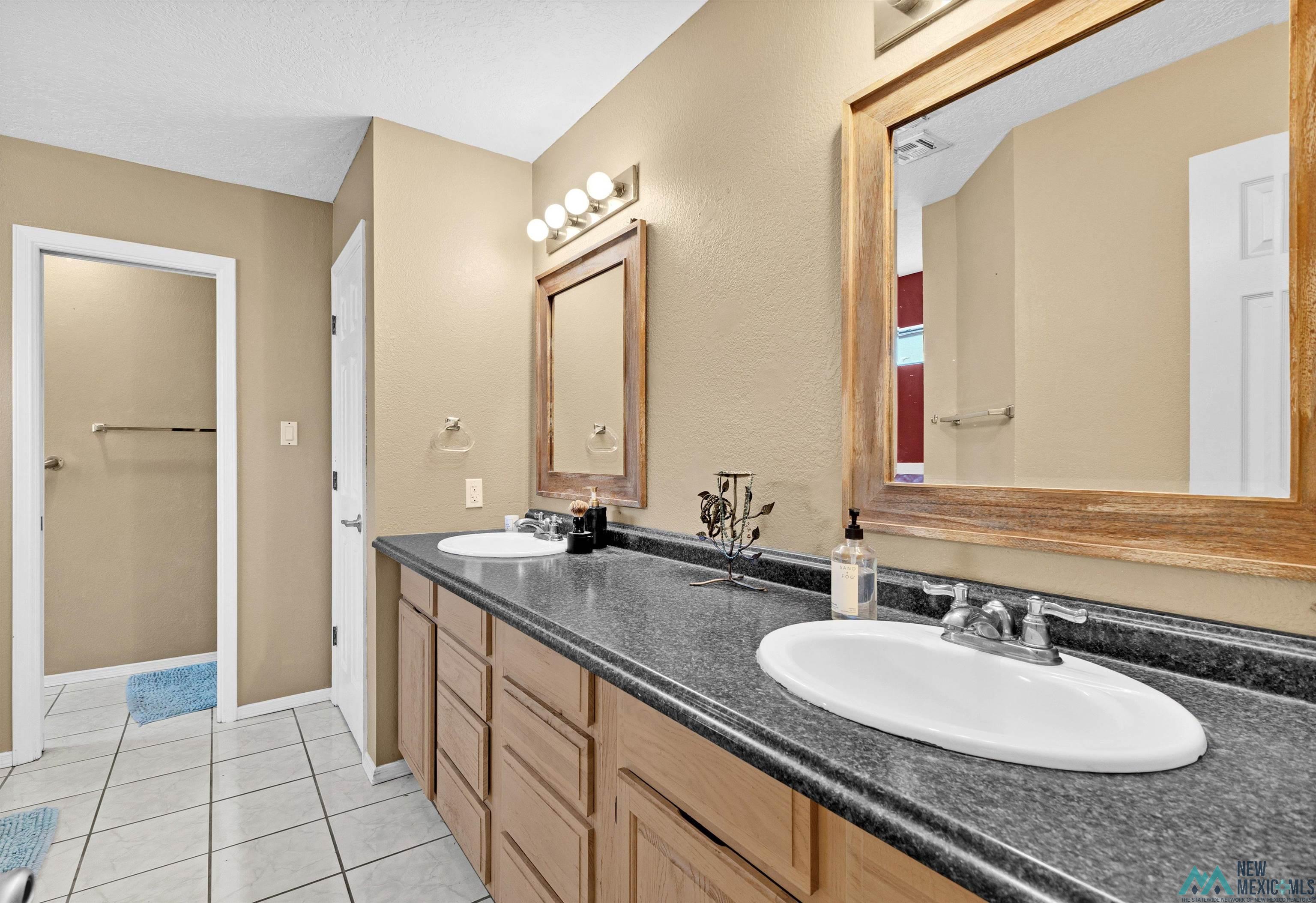 5008 Shadow Road Las Cruces, NM 88011 - Photo 23 of 35 Full bathroom with double vanity, light tile patterned floors, and a textured ceiling