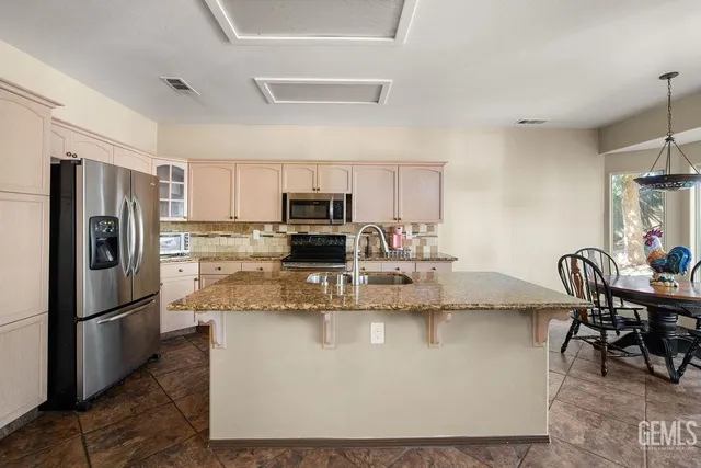 a kitchen with kitchen island a counter top space cabinets stainless steel appliances and a dining table