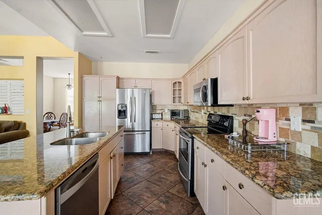 a kitchen with stainless steel appliances granite countertop a sink stove refrigerator and cabinets