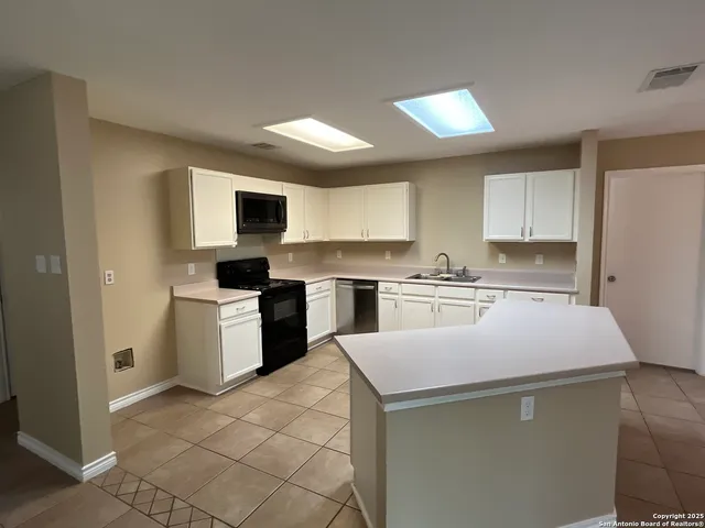 a kitchen with a sink a stove top oven and white stainless steel appliances