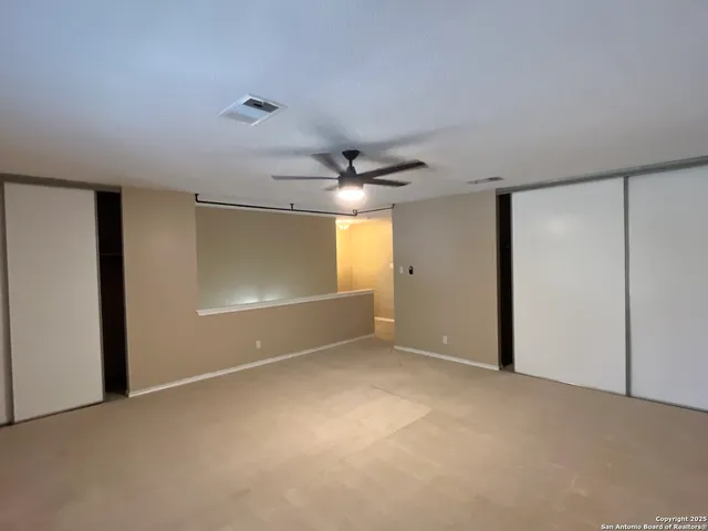 an empty room with a fan and a window