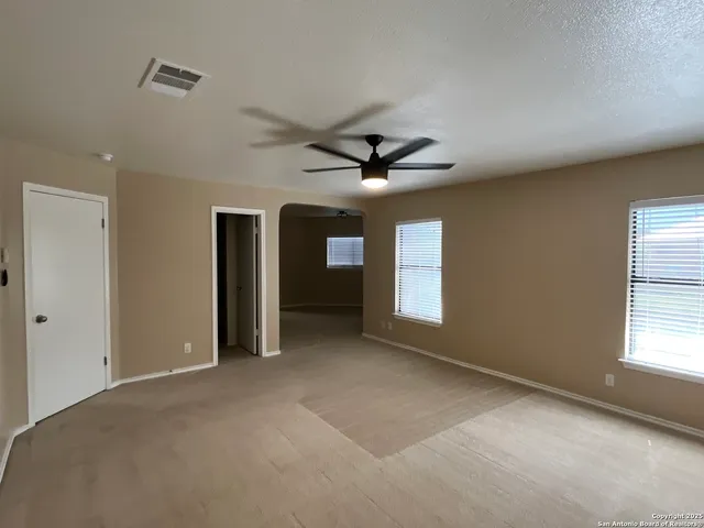 an empty room with a window and a ceiling fan