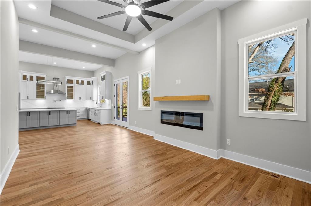 363 Marigna Avenue Scottdale, GA 30079 - Photo 14 of 33 an empty room with wooden floor a ceiling fan and a kitchen