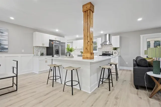 a kitchen with stainless steel appliances kitchen island granite countertop a table chairs and a refrigerator