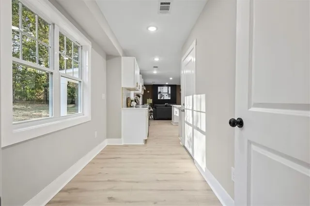 a view of an empty room with window and wooden floor