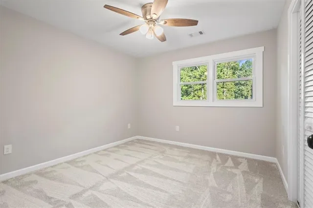 an empty room with closet and a chandelier fan