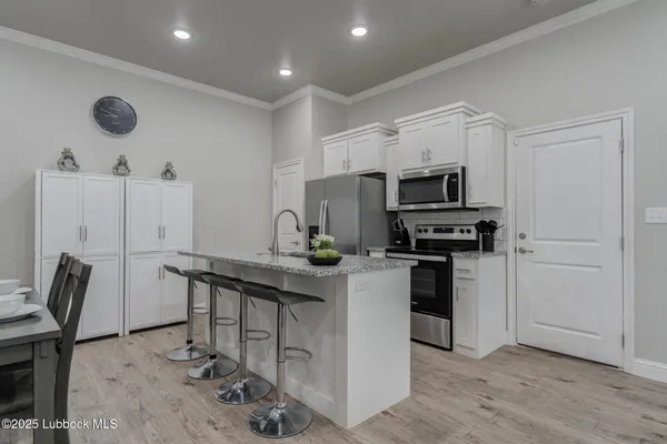 a kitchen with stainless steel appliances a stove a sink cabinets and wooden floor