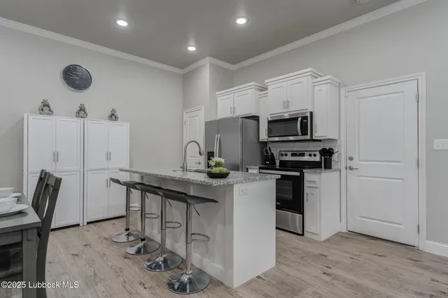 a kitchen with stainless steel appliances a stove a sink cabinets and wooden floor