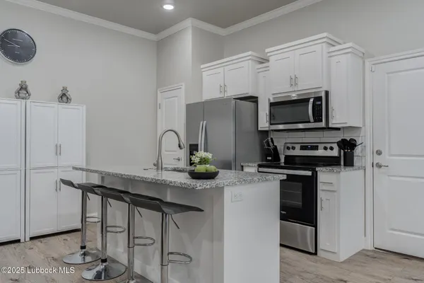 a kitchen with granite countertop a sink stainless steel appliances and white cabinets