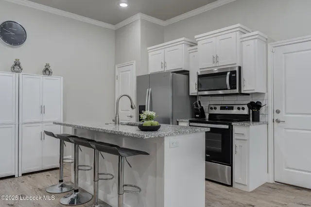 a kitchen with granite countertop a sink stainless steel appliances and white cabinets