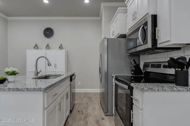 a kitchen with granite countertop a sink stainless steel appliances and cabinets