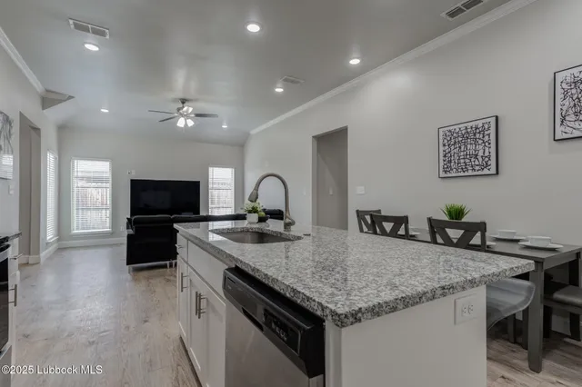 a kitchen with granite countertop kitchen island stainless steel appliances a sink and a refrigerator