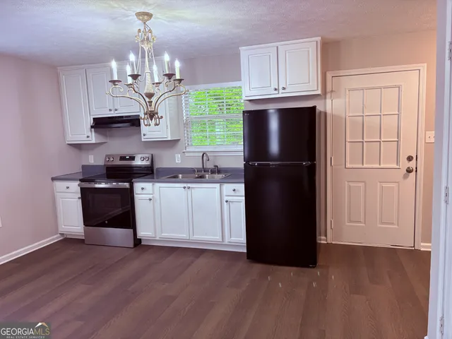 a kitchen with a refrigerator a sink and wooden floor