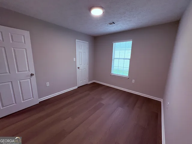 an empty room with wooden floor and window