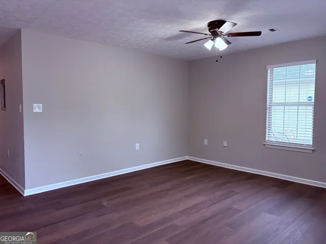 a view of a room with wooden floor and a ceiling fan