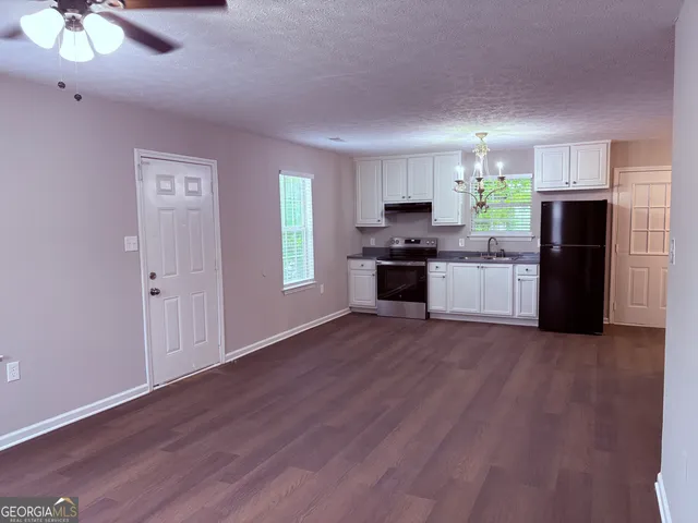 a large kitchen with hardwood floor a refrigerator and a stove top oven