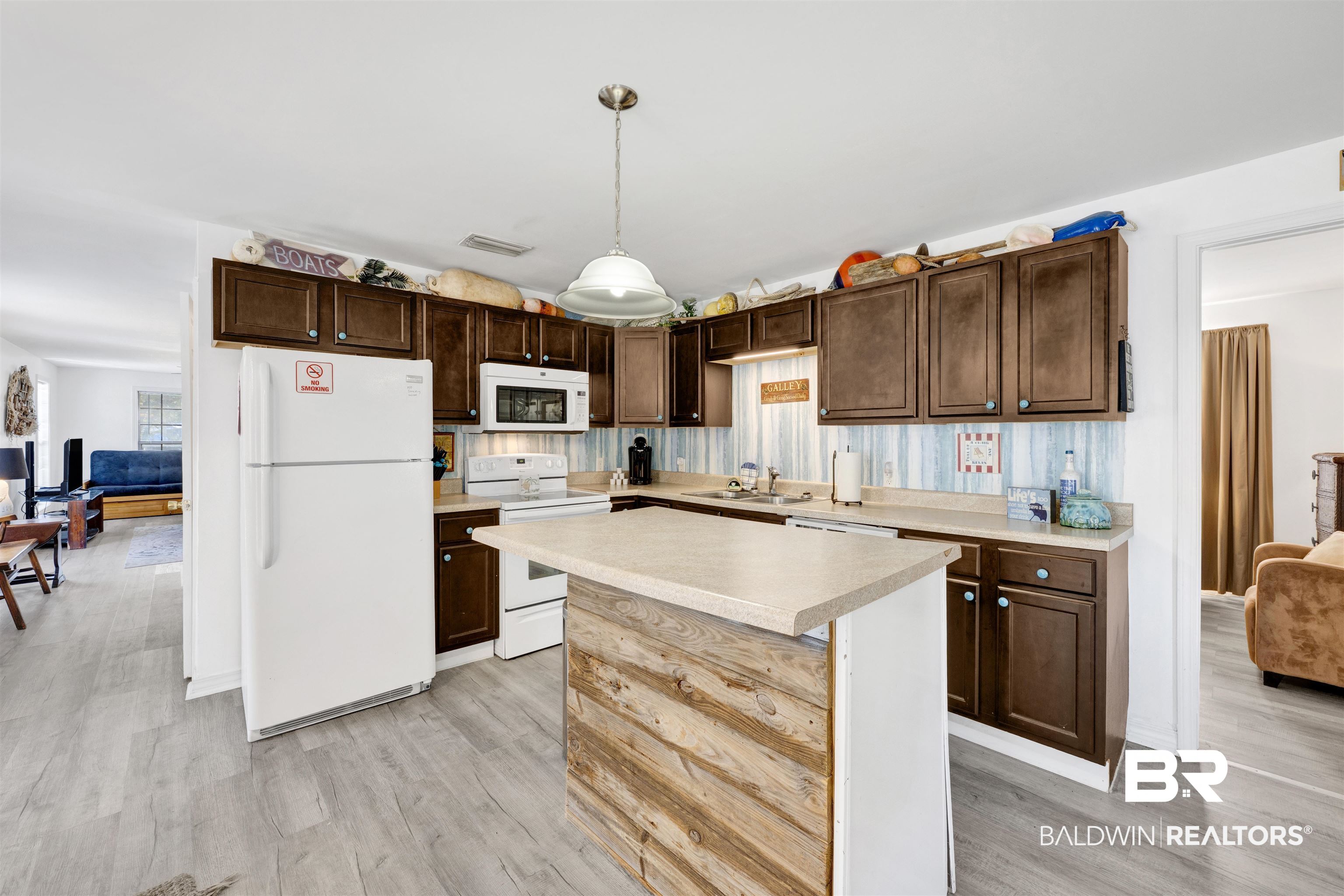 23770 Miflin Road Elberta, AL 36530 - Photo 8 of 38 Kitchen with light countertops, white appliances, dark brown cabinets, hanging light fixtures, and a kitchen island