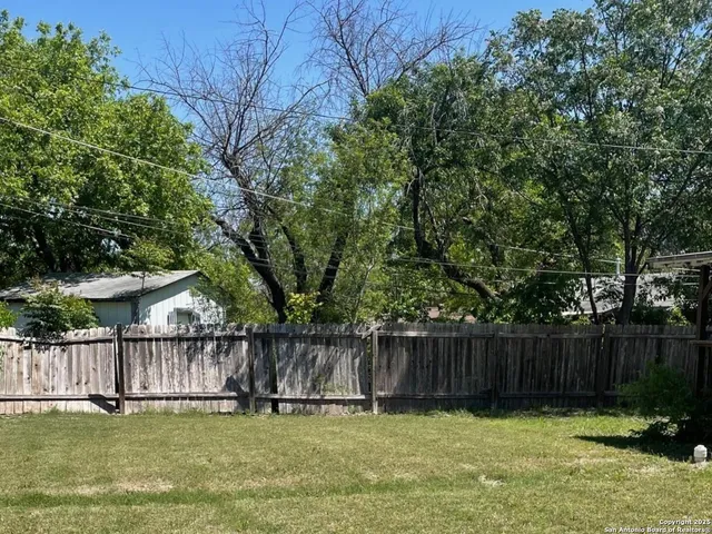 a view of a yard with a fence and trees