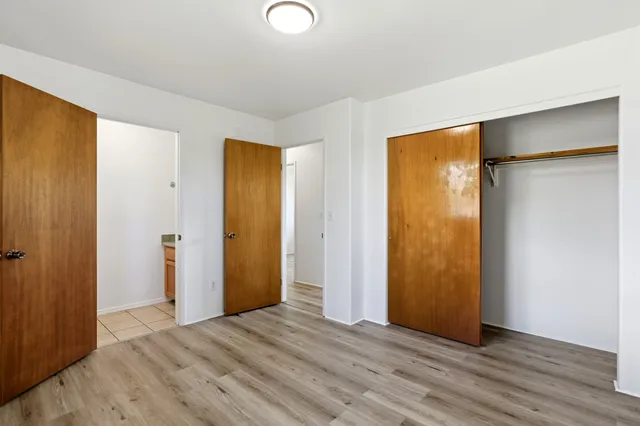 a view of an empty room with wooden floor and closet