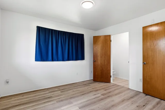 an empty room with wooden floor and closet area