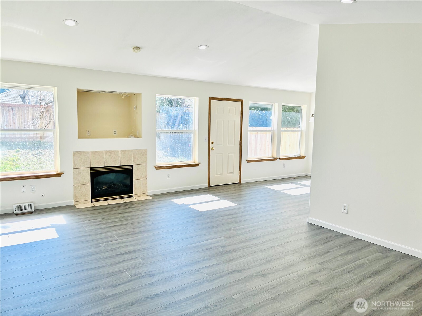 8802 222nd Street East Graham, WA 98338 - Photo 5 of 25 an empty room with wooden floor fireplace and windows
