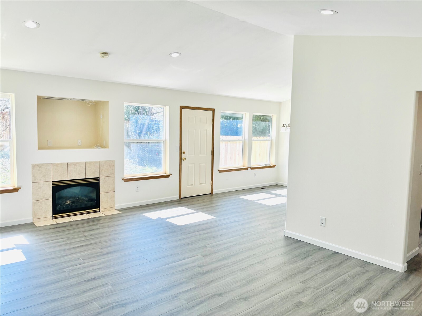 8802 222nd Street East Graham, WA 98338 - Photo 7 of 25 an empty room with wooden floor fireplace and windows