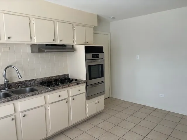 a kitchen with granite countertop white cabinets and stainless steel appliances