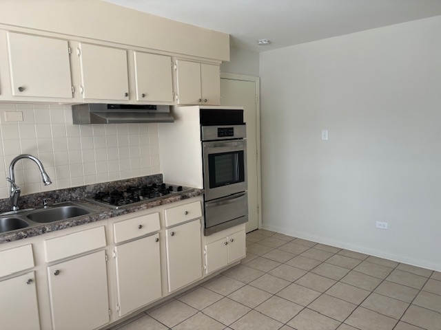 372 Yates Avenue, Unit 3 Calumet City, IL 60409 - Photo 10 of 12 a kitchen with granite countertop white cabinets and stainless steel appliances